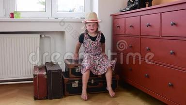 可爱的小女孩坐在老式的手提箱上，等待开始度假。 小女孩穿<strong>花裙子</strong>。 旅行